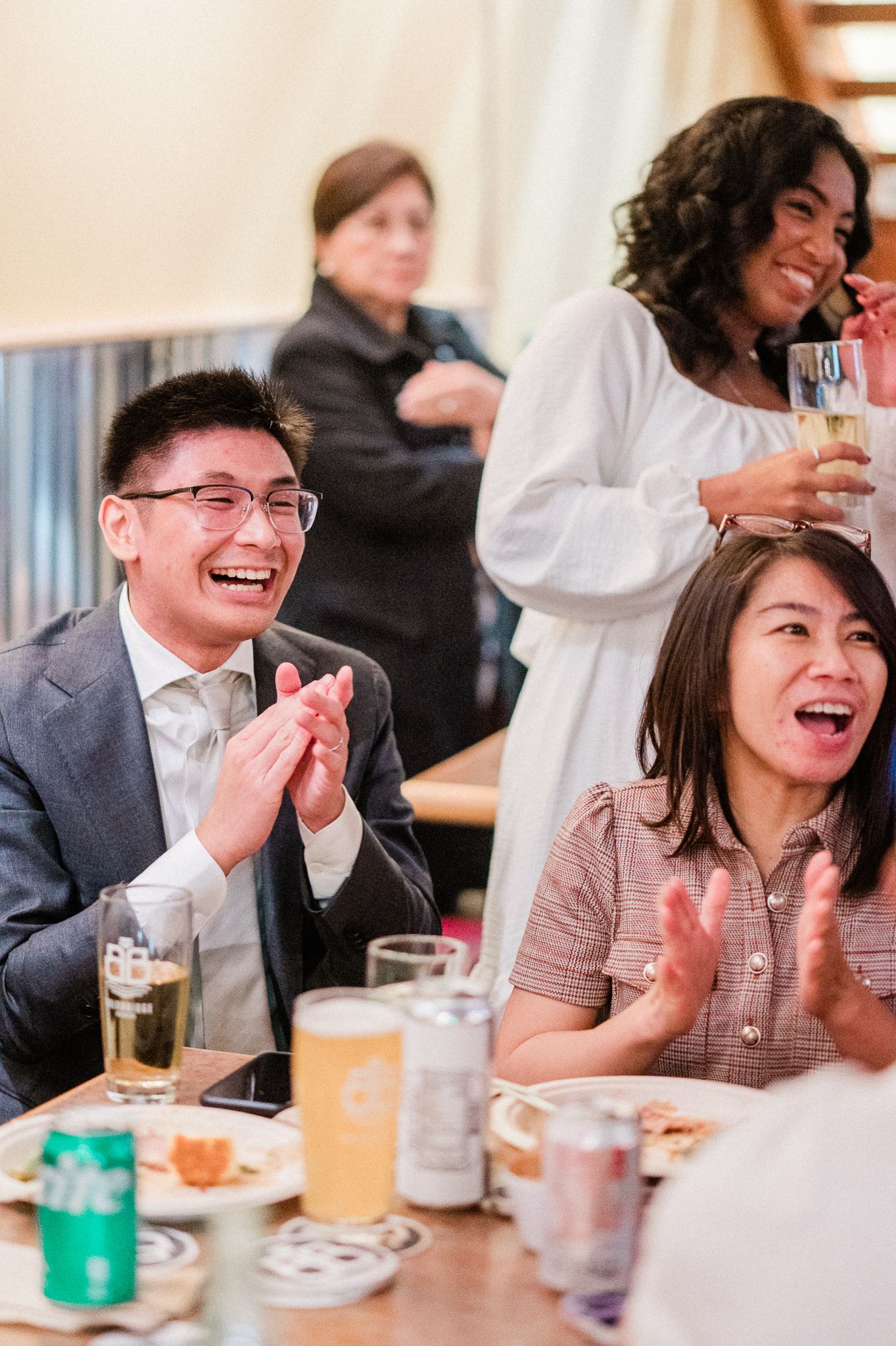 A group of friends laugh and smile while enjoying drinks and conversation at a casual dining gathering