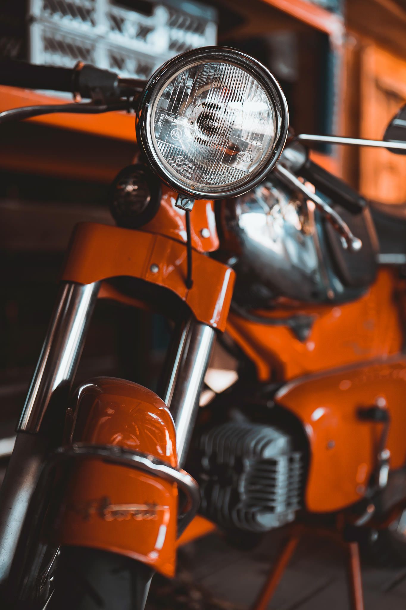 Close-up of a vintage orange motorcycle headlight with chrome details.