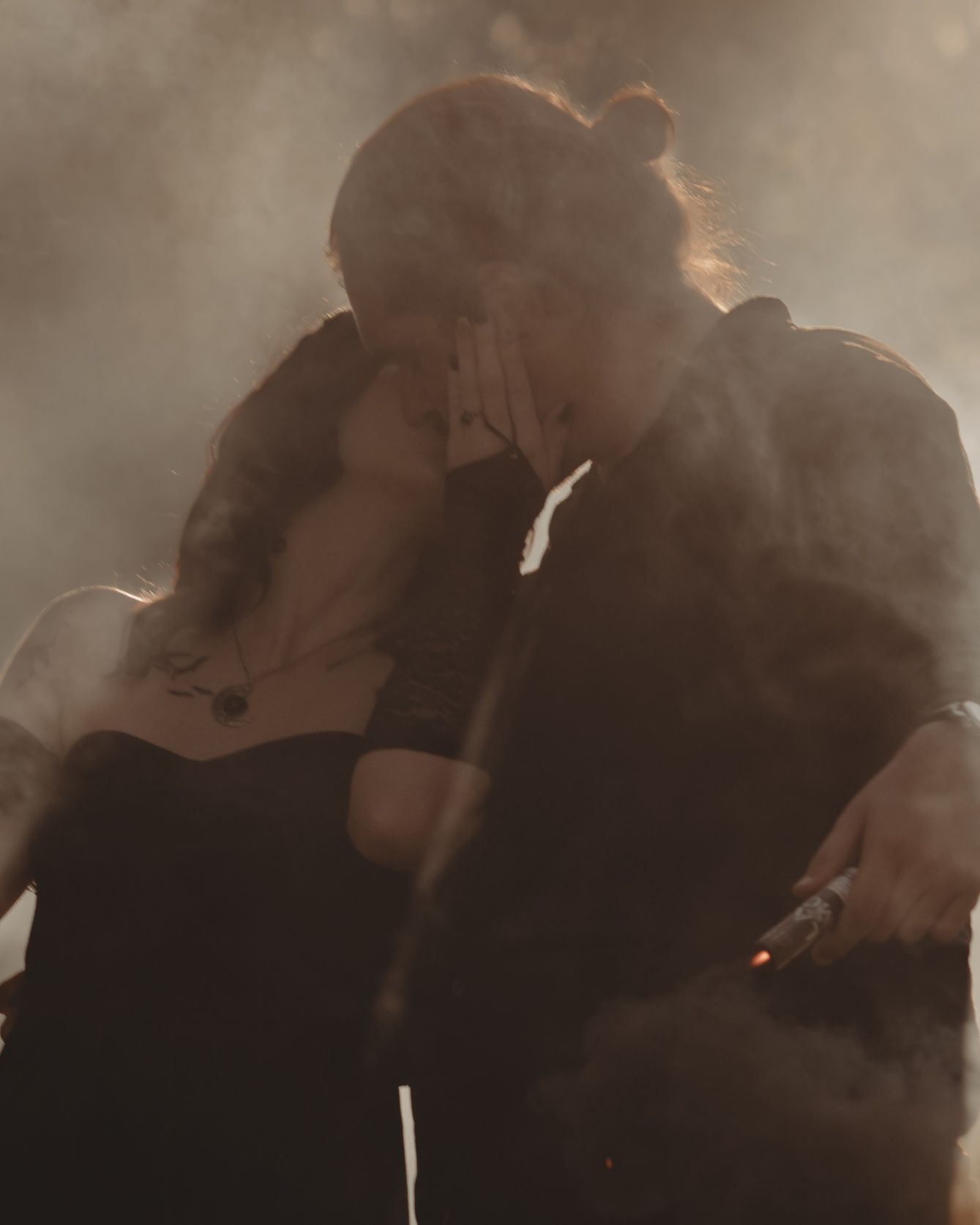 Romantic couple embraces in intimate silhouette against warm lighting during sunset photoshoot.