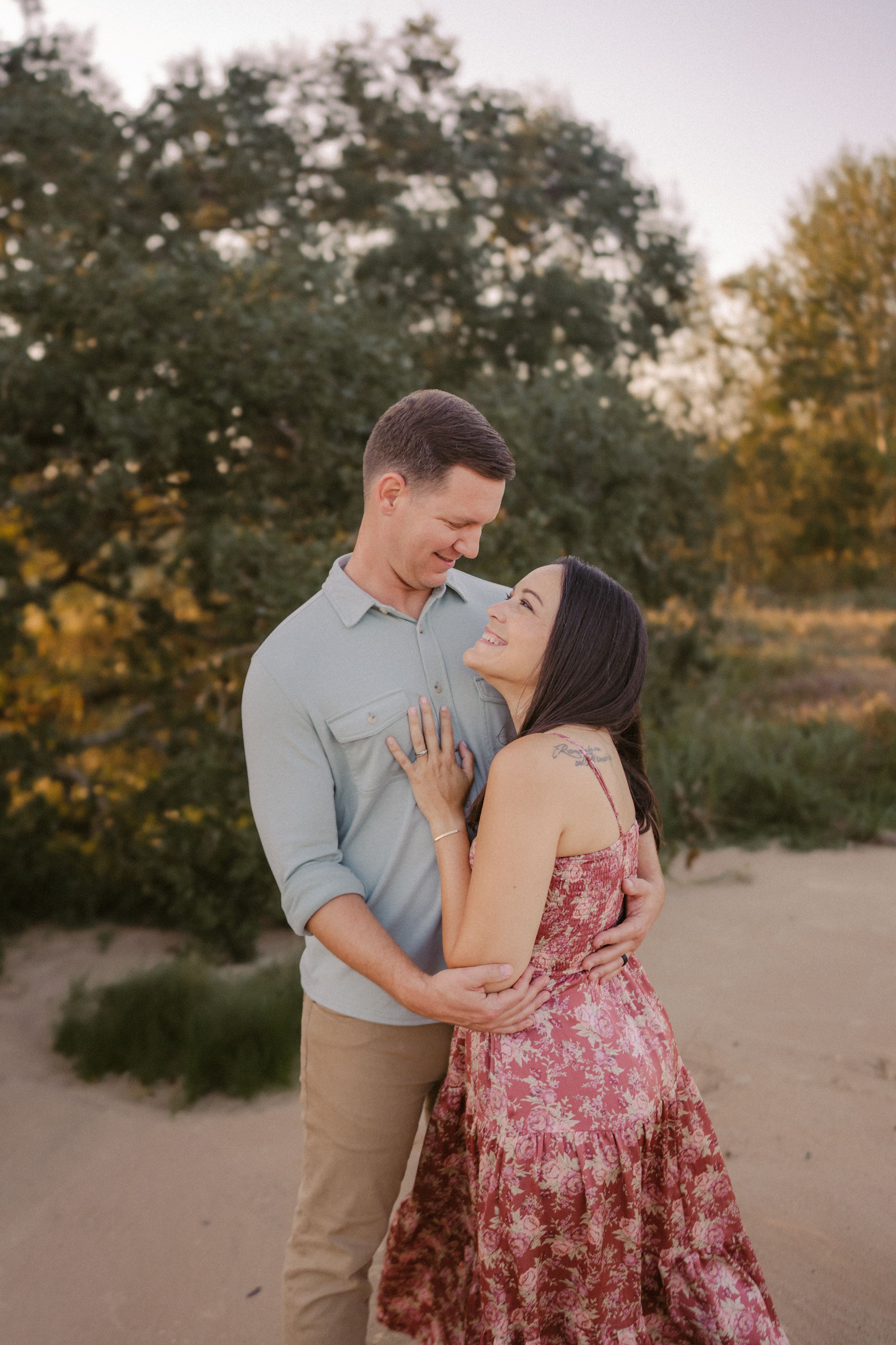 A romantic couple embraces while sharing tender moments together on a nature trail at sunset.
