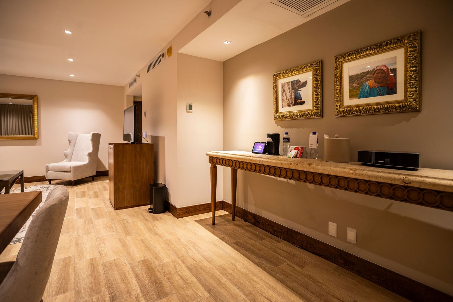 Upscale hotel lobby with console table, framed artwork, light wood floors, and warm neutral tones.
