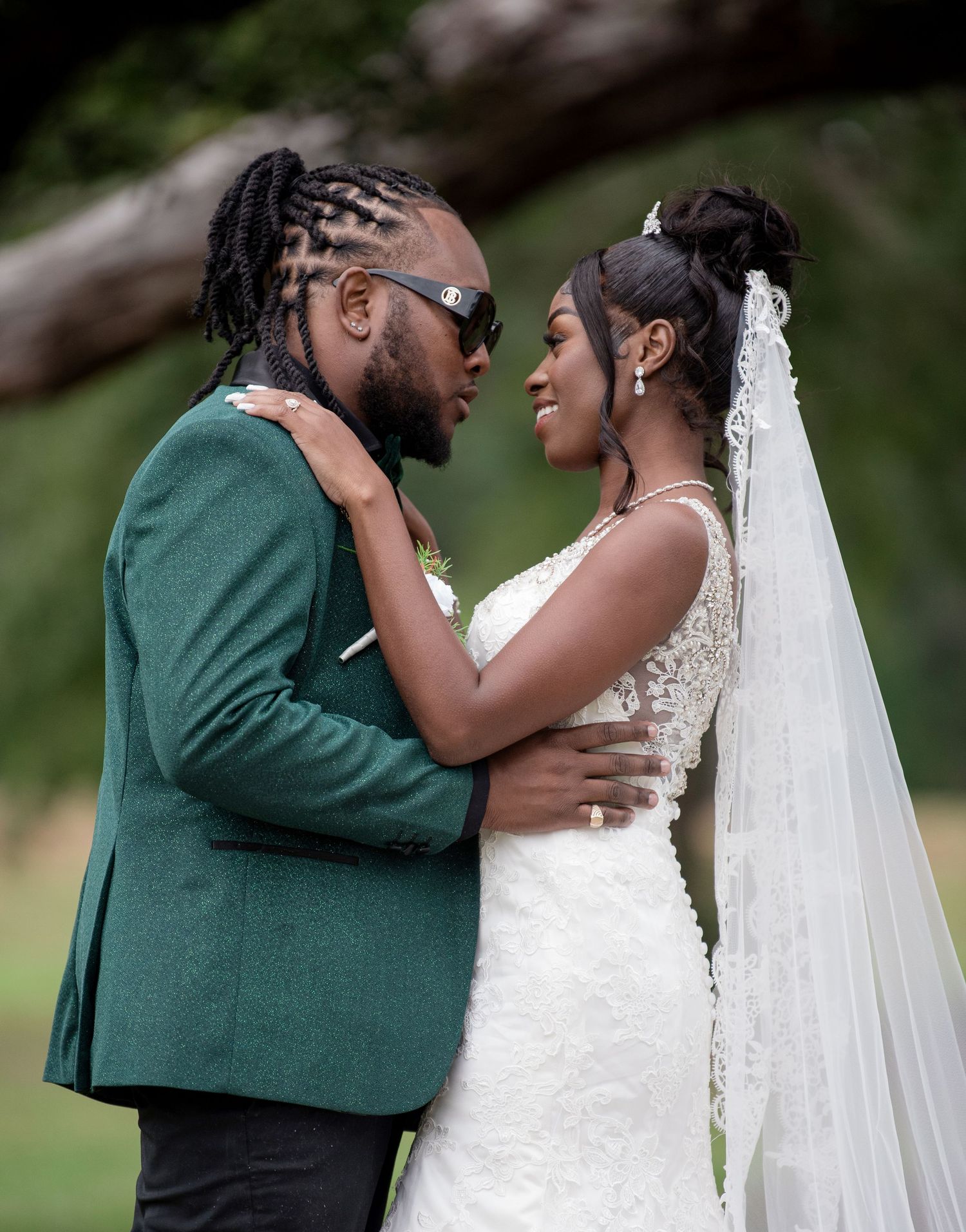 A joyful couple shares an intimate moment on their wedding day, with the bride in white and groom in emerald green.