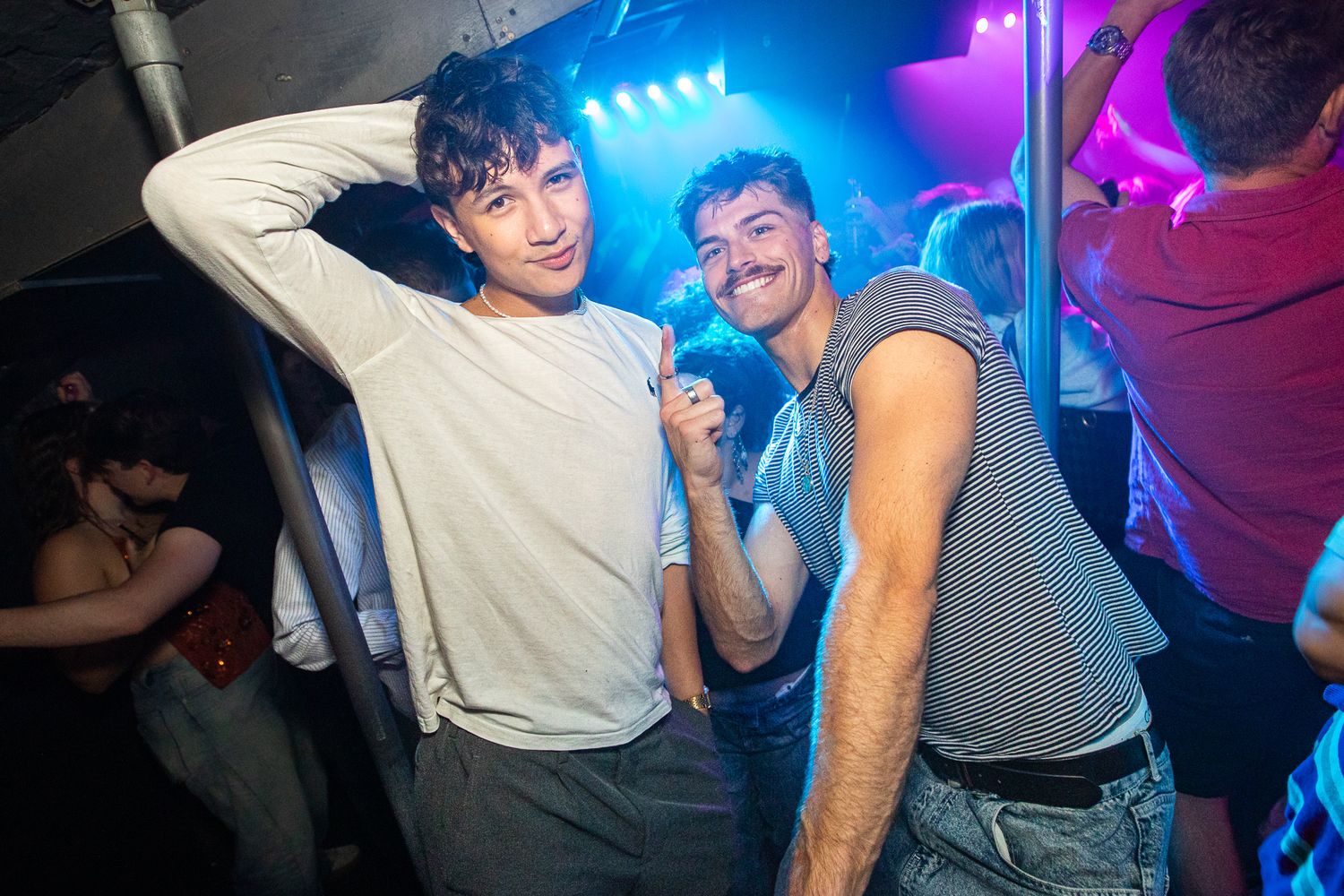 Energetic nightclub scene with colorful lighting and people dancing in a lively atmosphere.