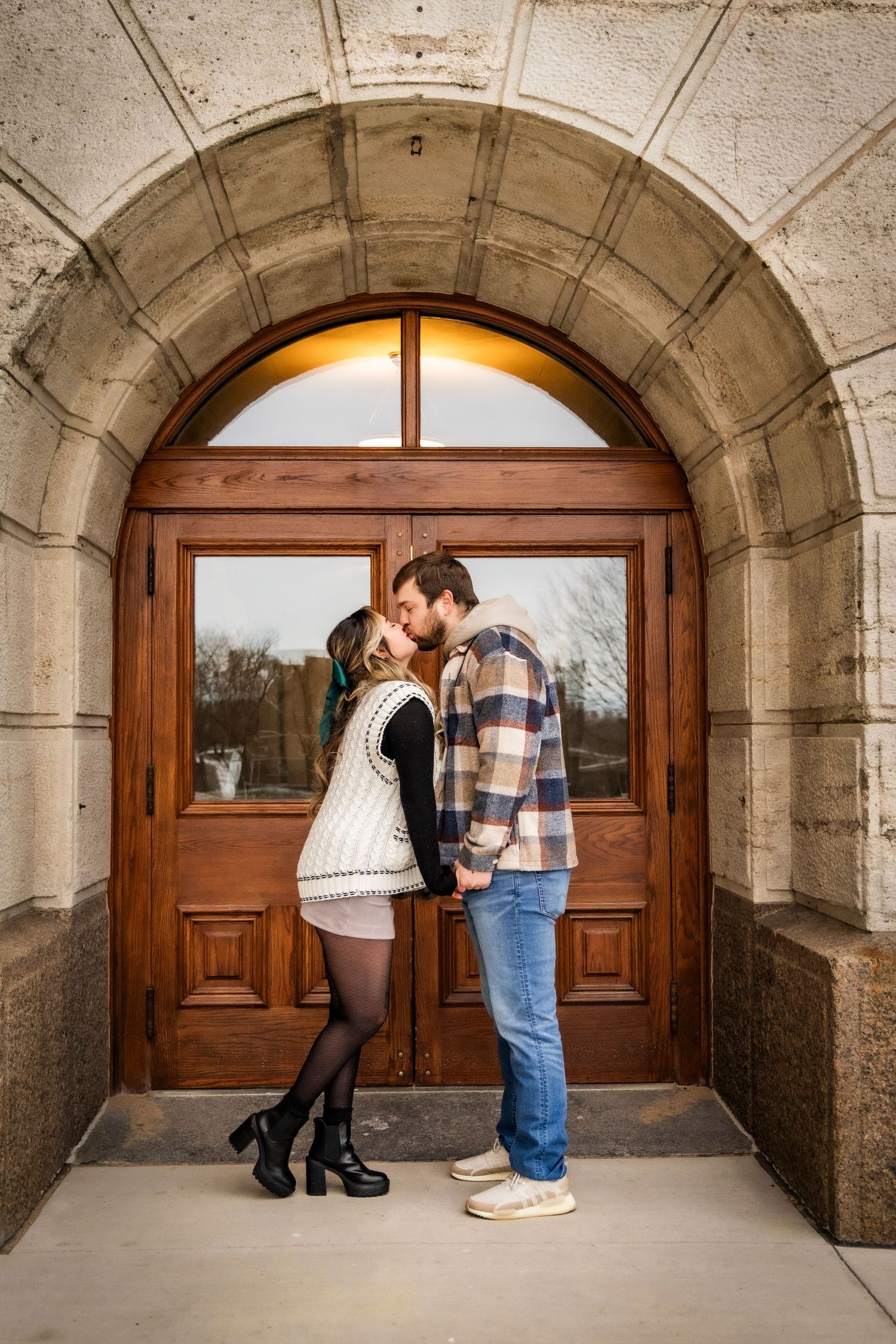 Couple kissing at the Iowa State Capital by their entrance doors