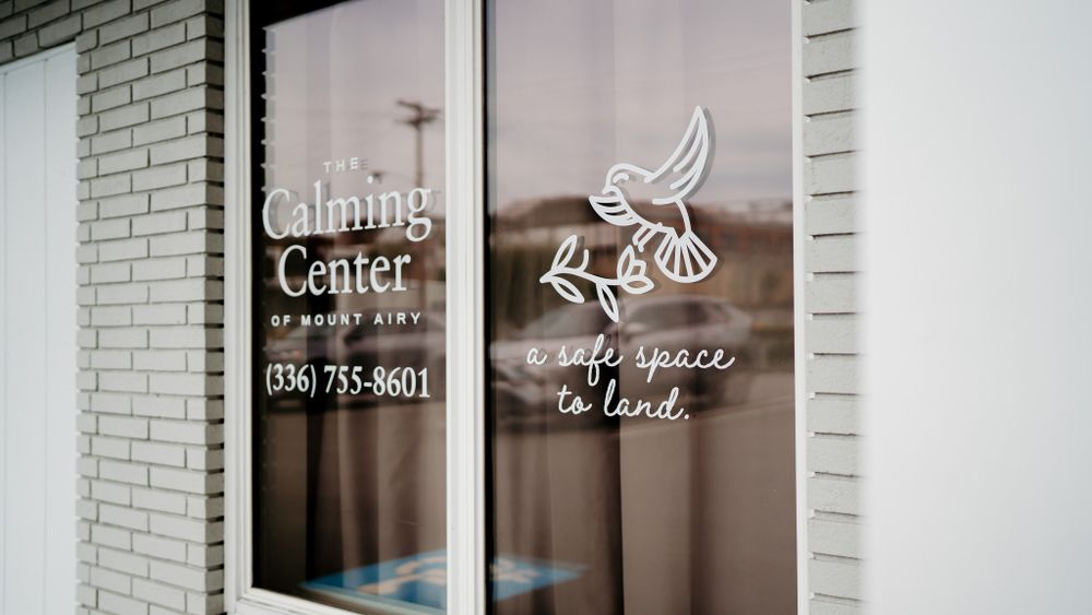 White storefront window with dove logo and text for a healing center.