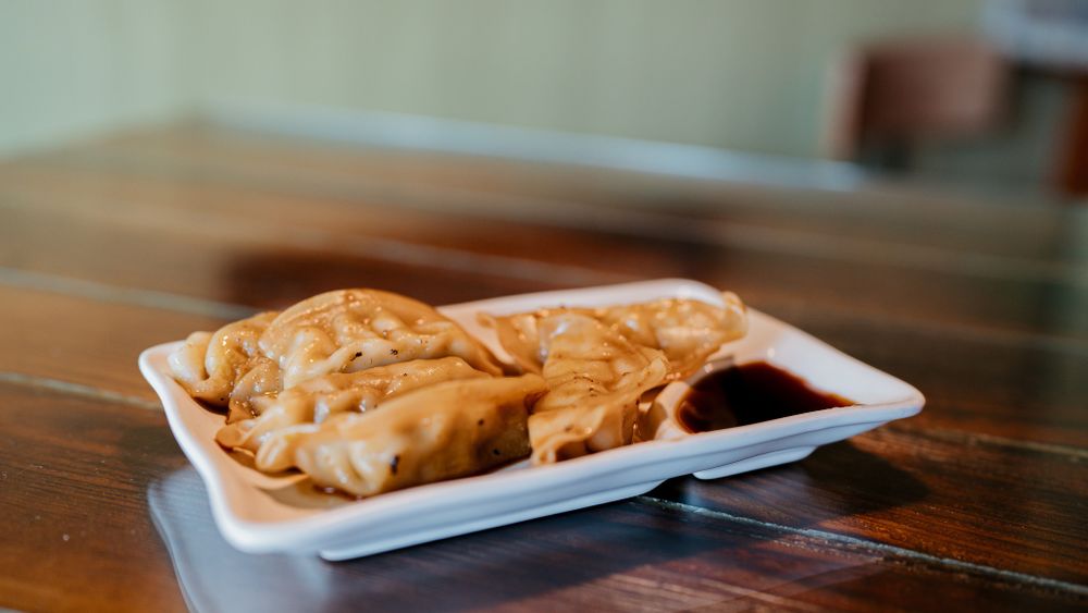 Golden fried dumplings or empanadas served on a white paper tray.