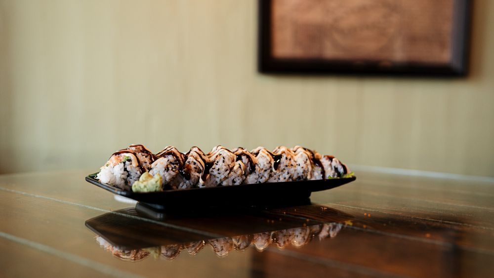 Chocolate dessert rolls drizzled with sauce arranged on a black serving plate.
