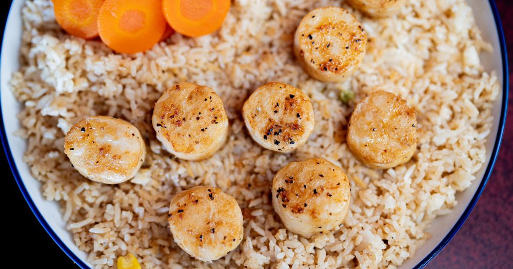 Seared scallops served over rice with mandarin oranges.