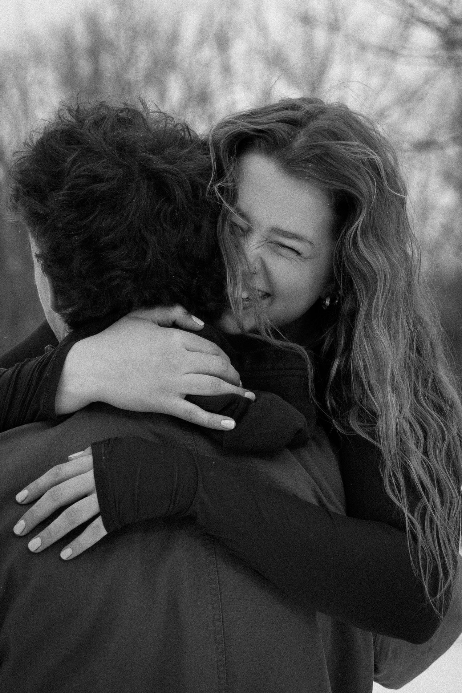 An intimate black and white photo captures two people sharing a warm embrace.