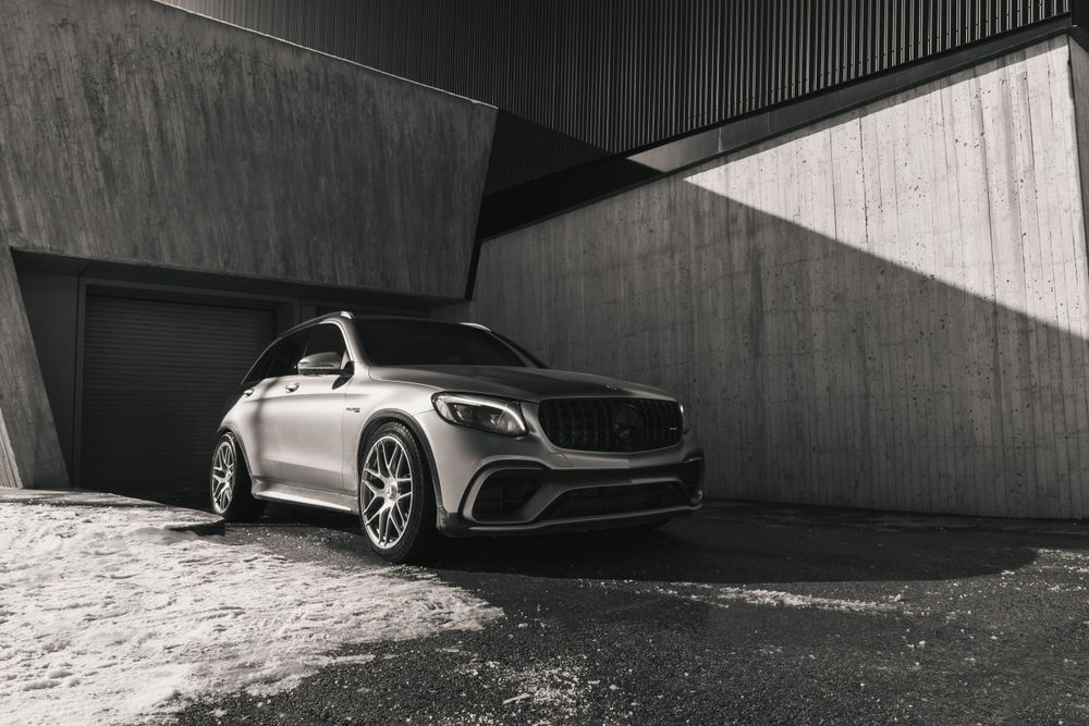 A sleek silver Mercedes-Benz SUV parked in a concrete parking structure with dramatic lighting.