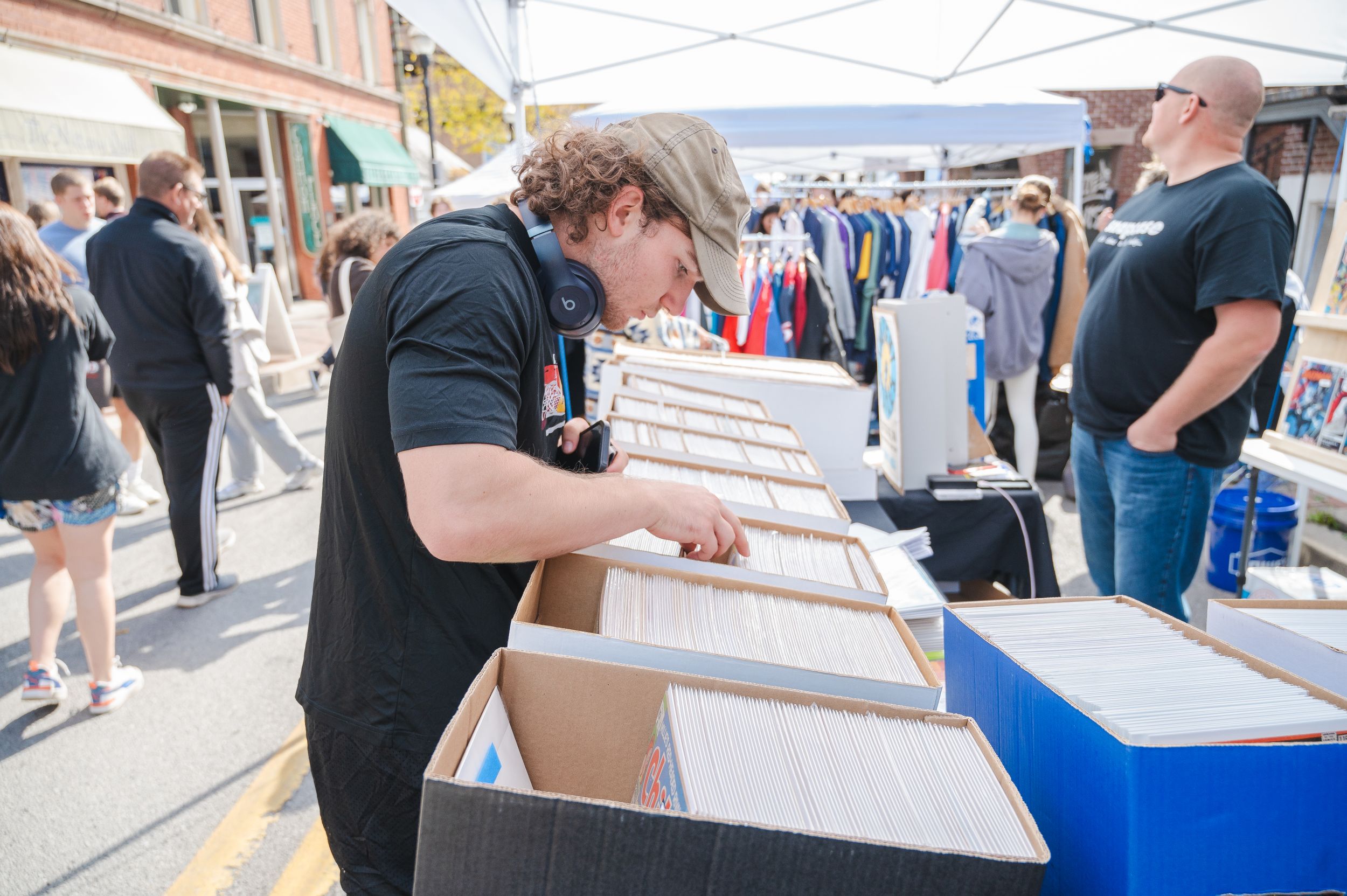 Customer browsing through vinyl records at an outdoor market stall.
