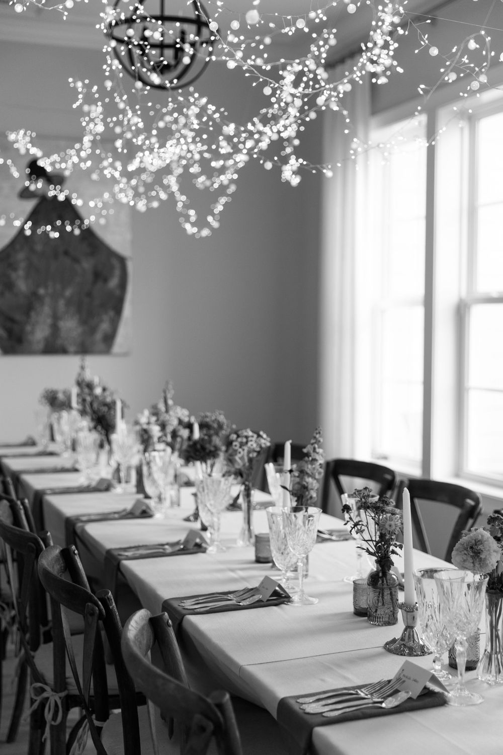 Elegant black and white wedding reception table setting with hanging twinkle lights.
