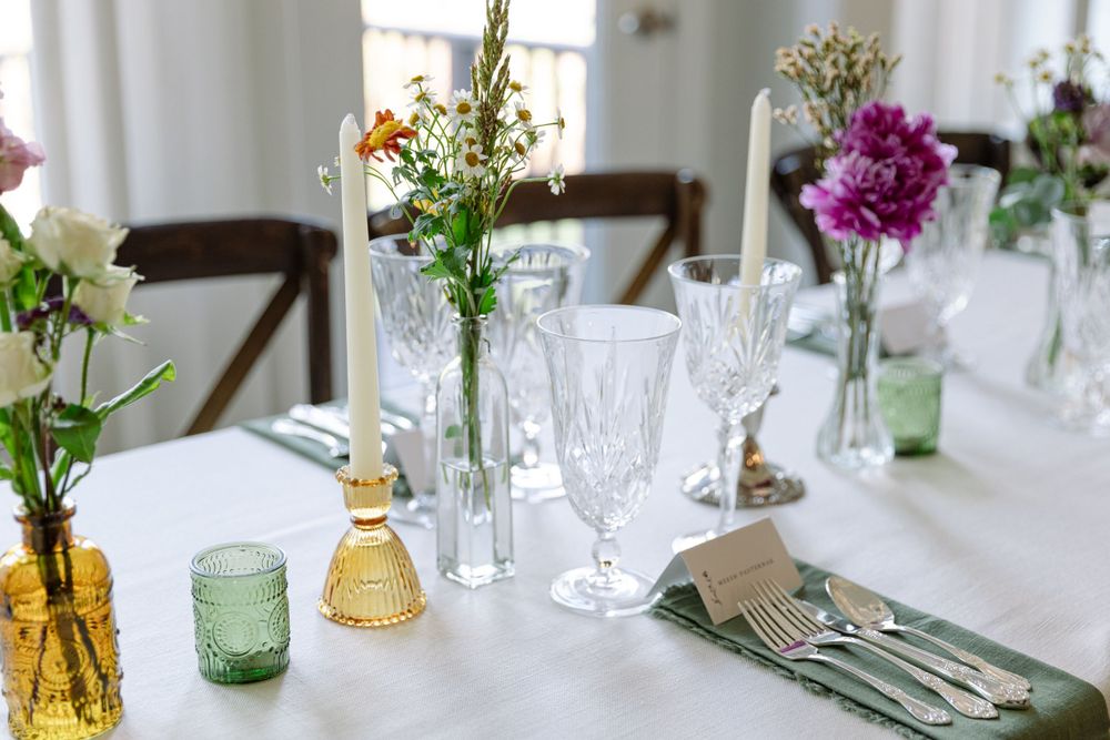 Wedding reception table with colorful floral centerpieces, crystal glasses and place settings.