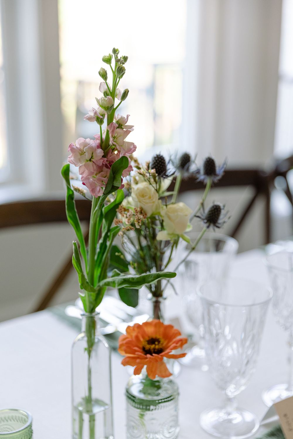 Close-up of delicate floral centerpiece with pink snapdragons and orange poppies in glass vases.