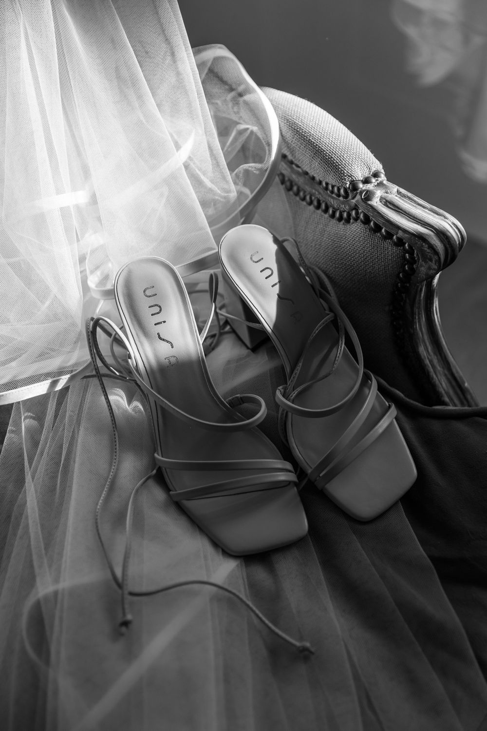 Elegant bridal shoes and veil arranged in dramatic black and white composition.
