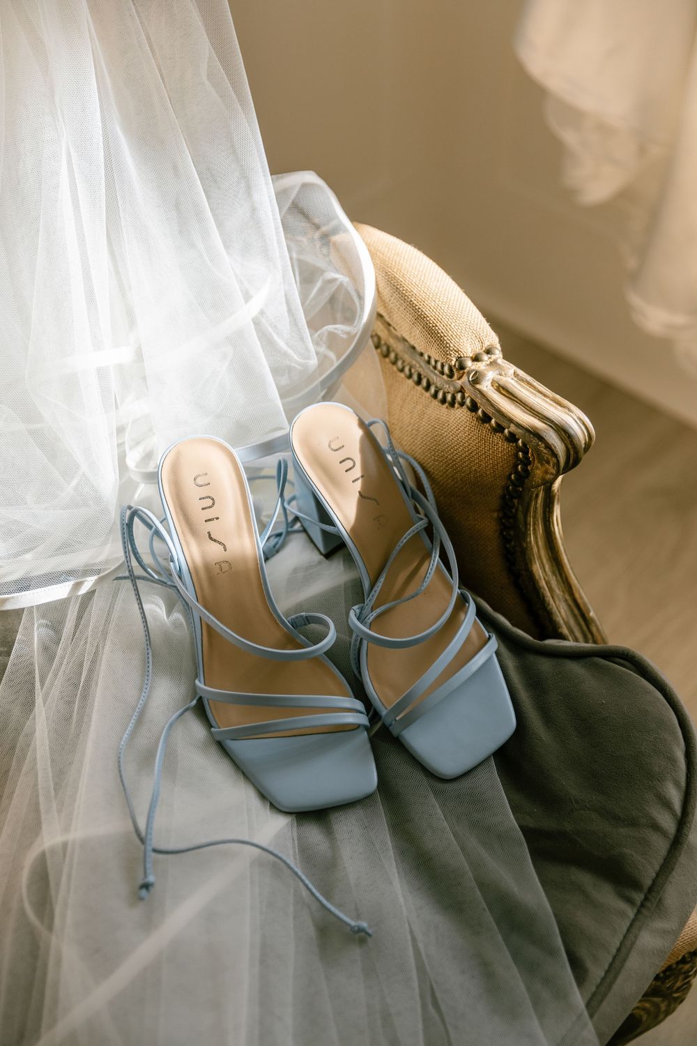Light blue strappy bridal sandals displayed with white tulle veil.