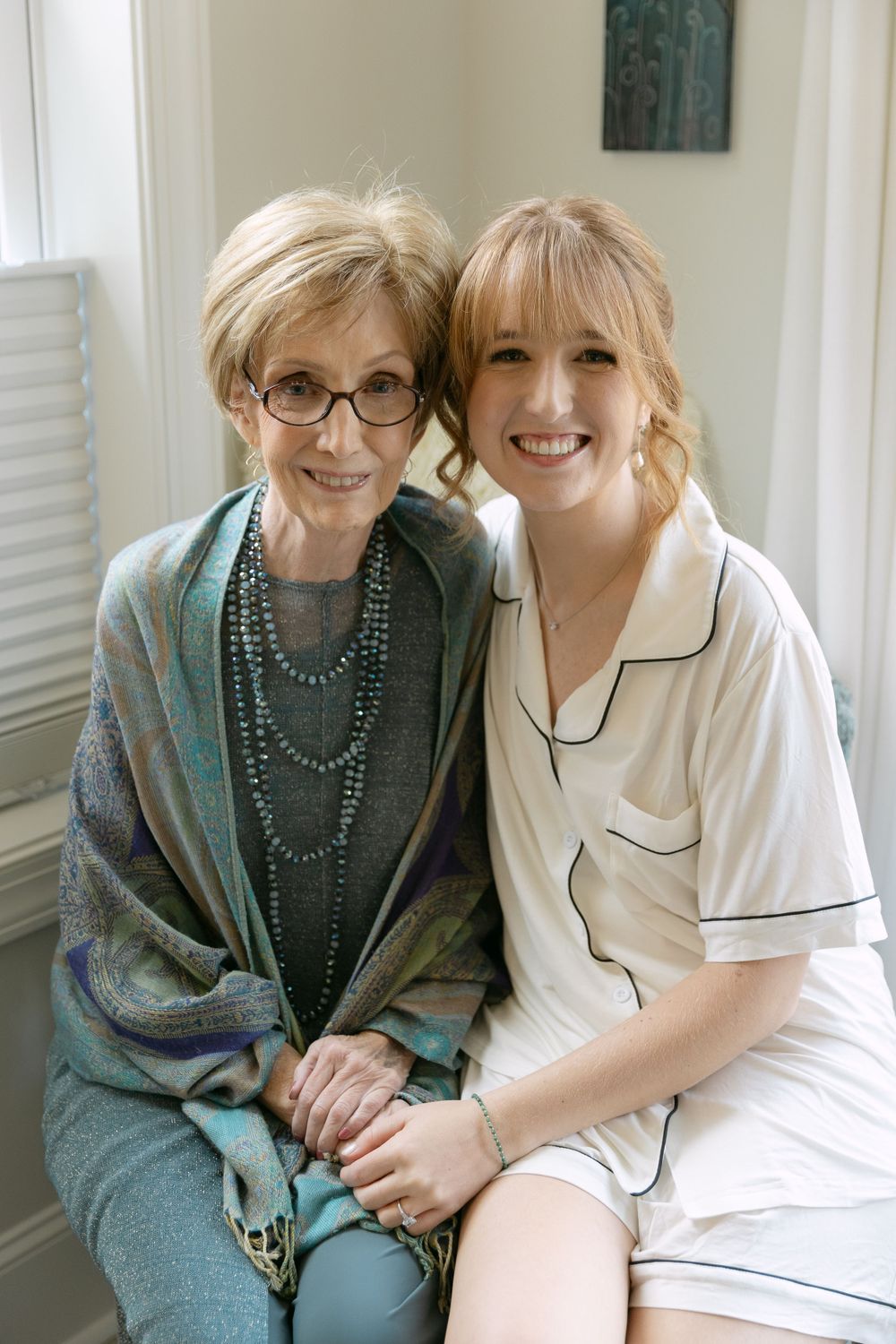 Two people sitting together in a bright window-lit room.