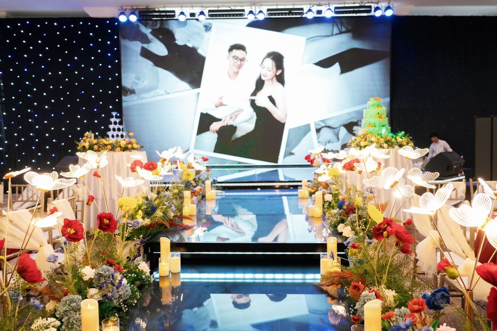 Elegant wedding venue setup with floral arrangements and projection screens displaying romantic imagery.