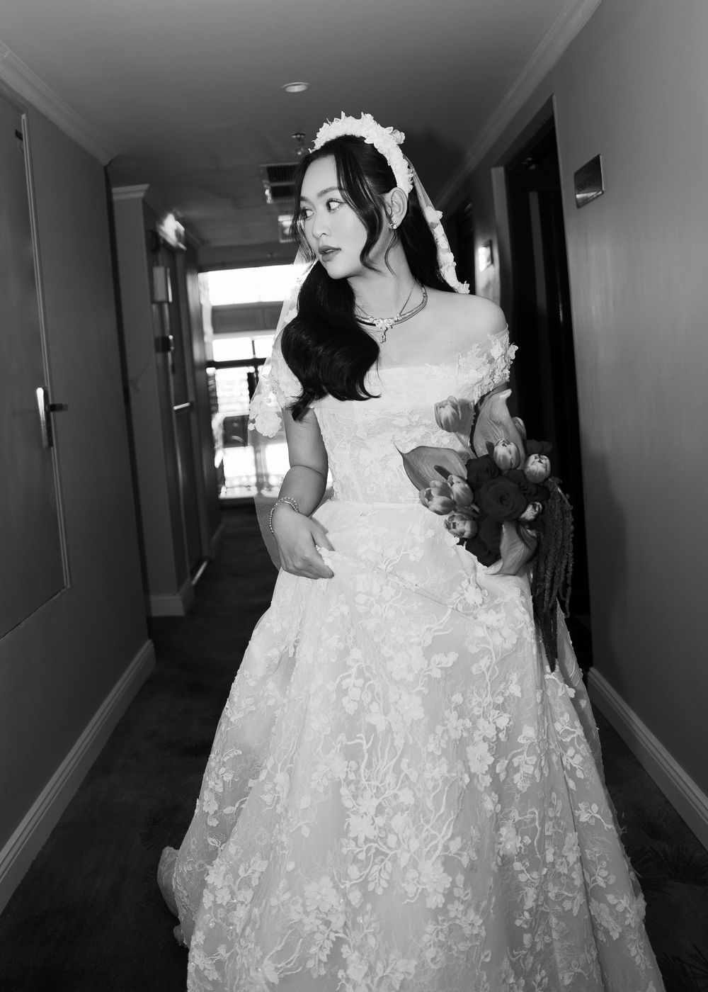 Wedding portrait in a corridor showing elegant white lace gown and floral details.