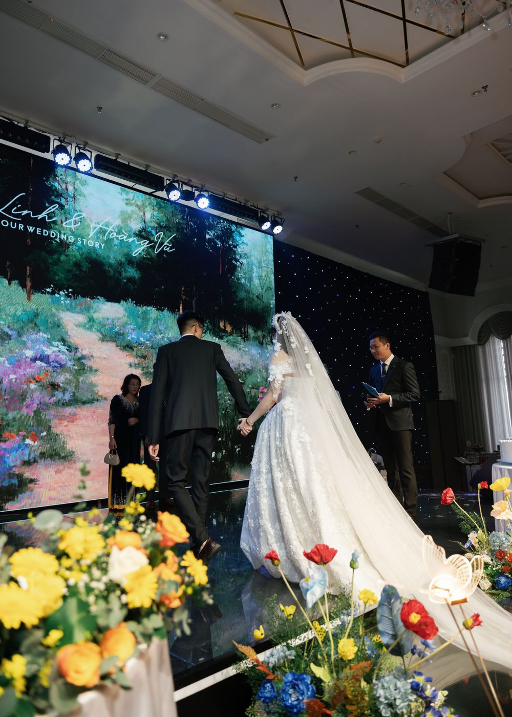 Wedding ceremony setup with dramatic backdrop screen and yellow floral decorations.