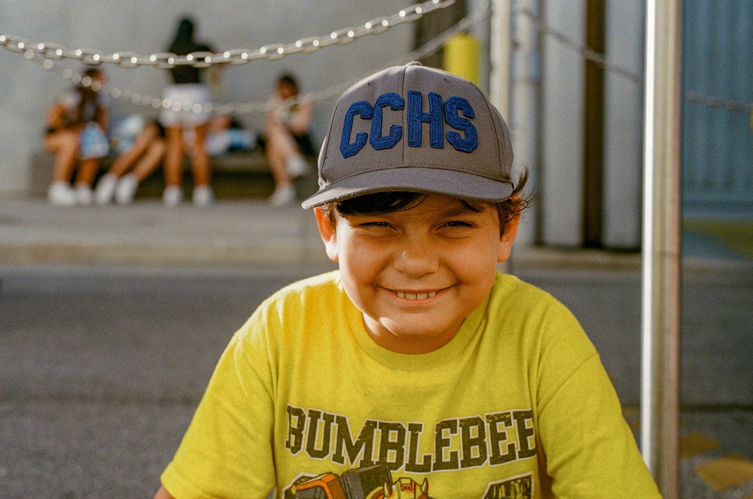 Person in yellow t-shirt and baseball cap smiling outdoors.