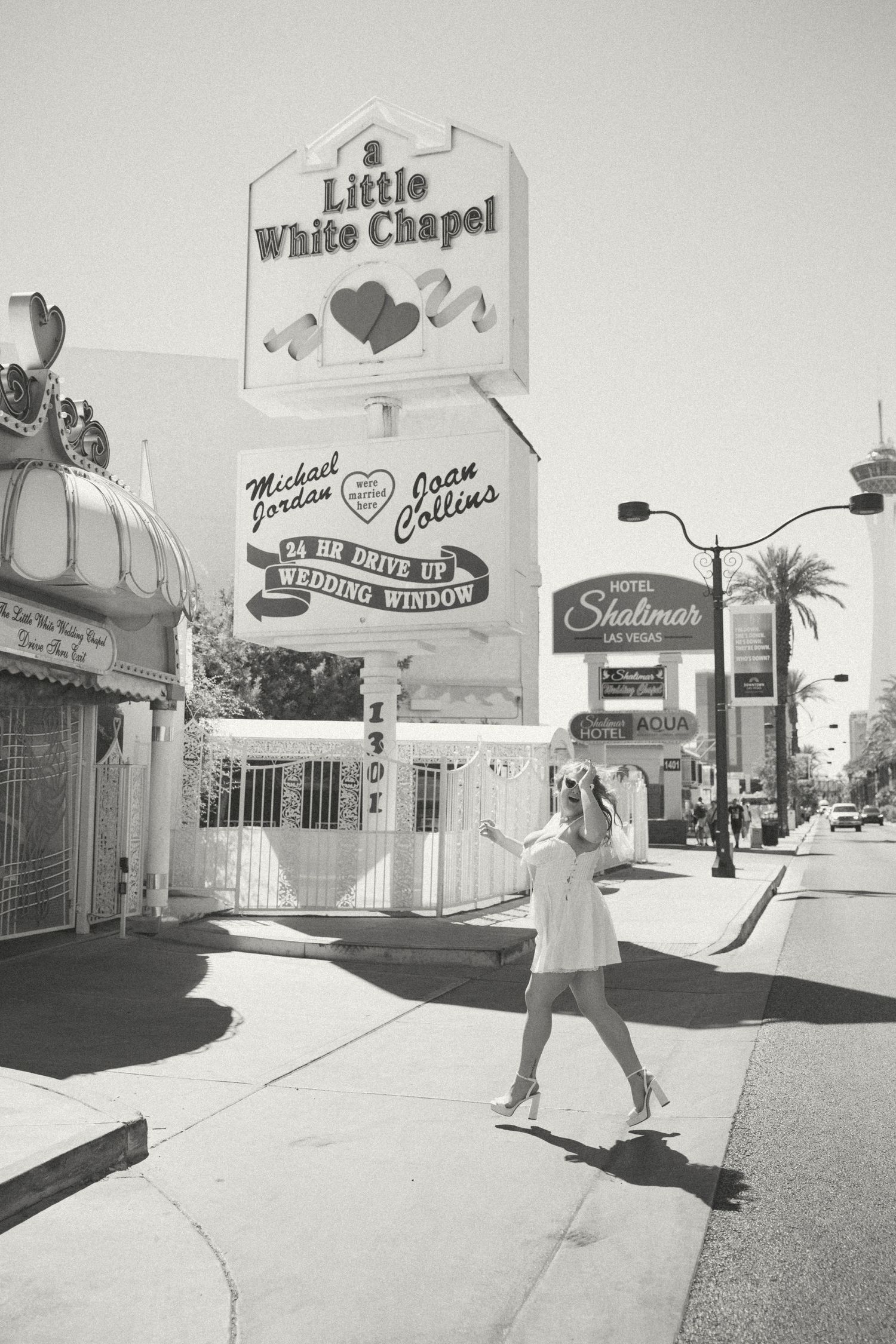 A black and white photo captures a bride dancing outside the Little White Chapel in Las Vegas.