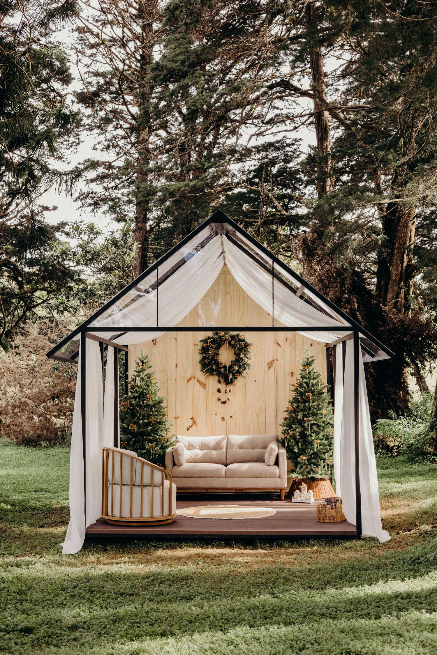 Rustic outdoor lounge setup with four matching canvas-covered gazebos featuring daybeds and cushions in a wooded setting.