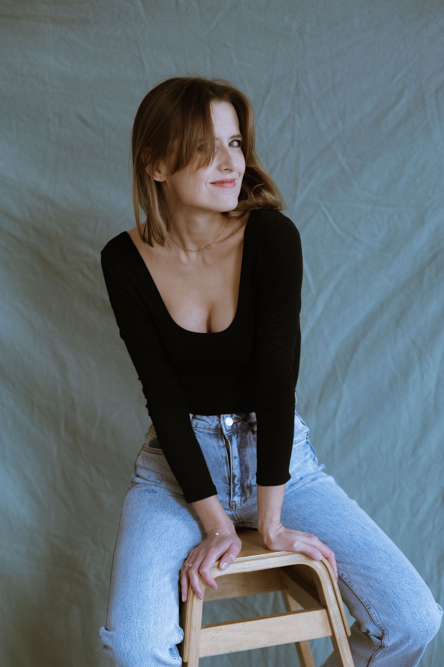 Kobieta na drewnianym krześle w studio fotograficznym.