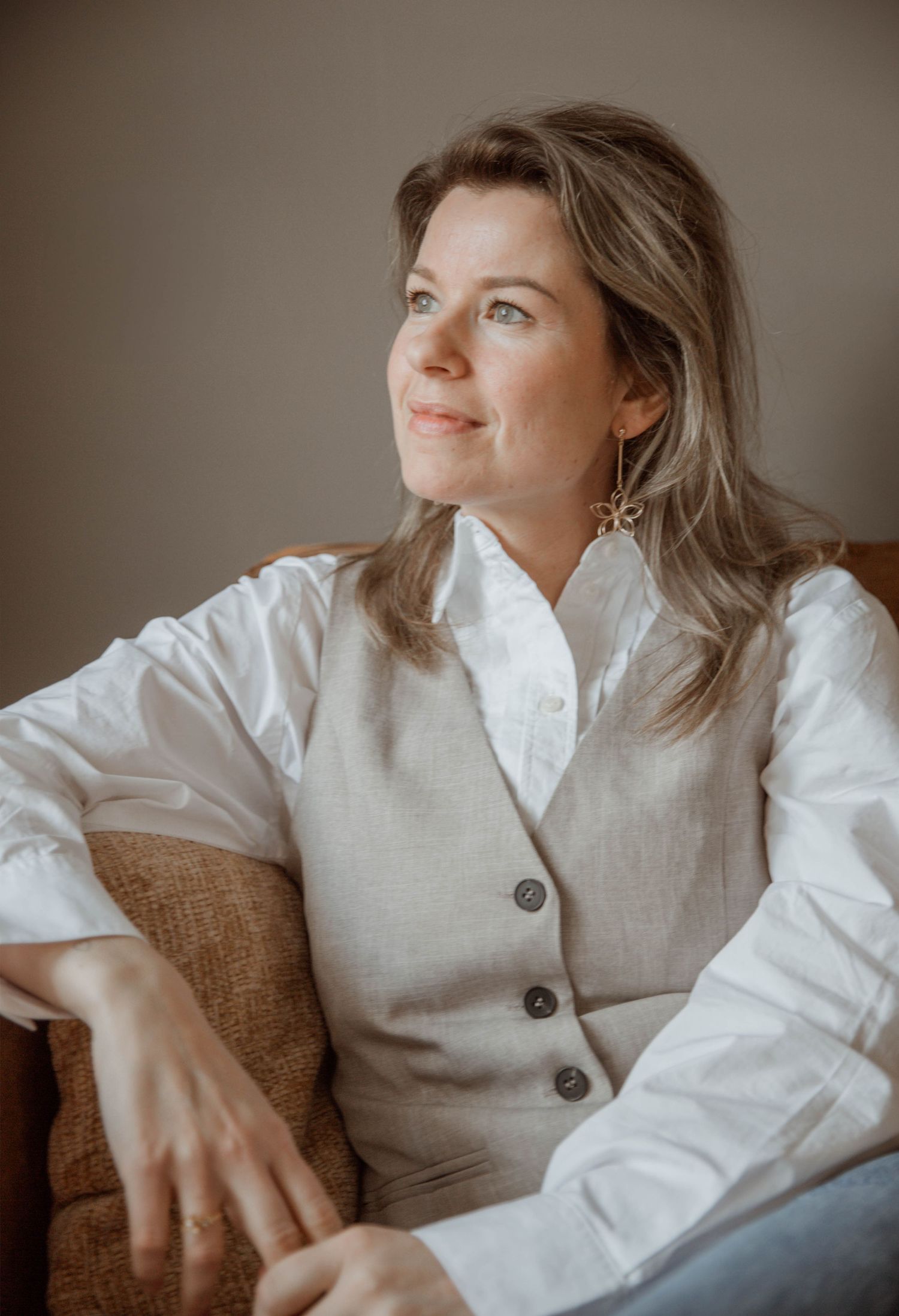Business casual portraits of someone in a white shirt and beige vest against neutral background.