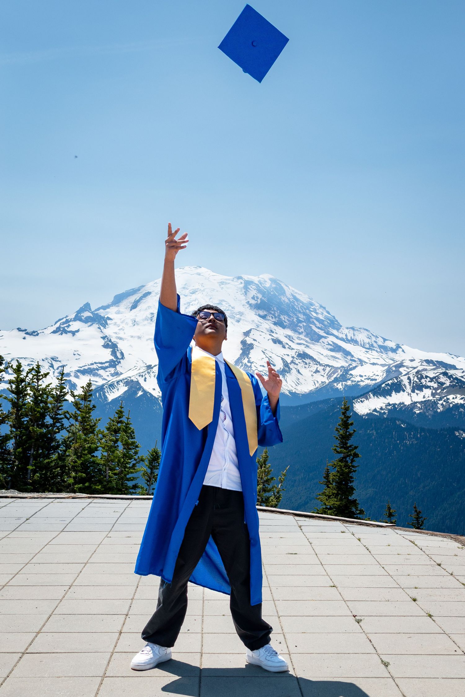 Graduation cap toss captured at Crystal Mountain with Mount Rainier in the background during midday senior session.