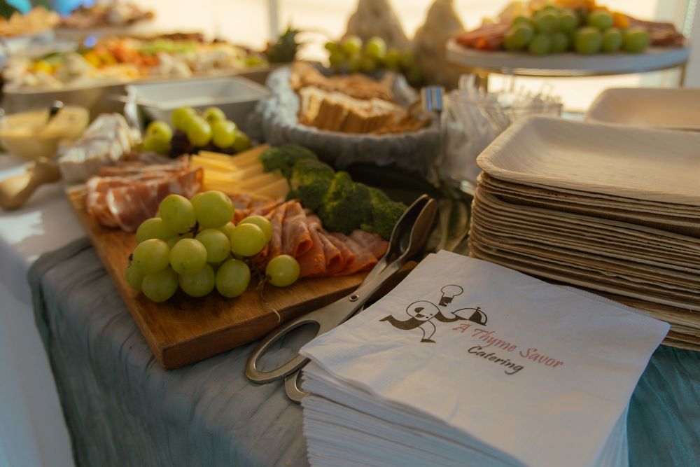 An elegant buffet spread featuring charcuterie boards with grapes, meats and cheeses alongside formal place settings.