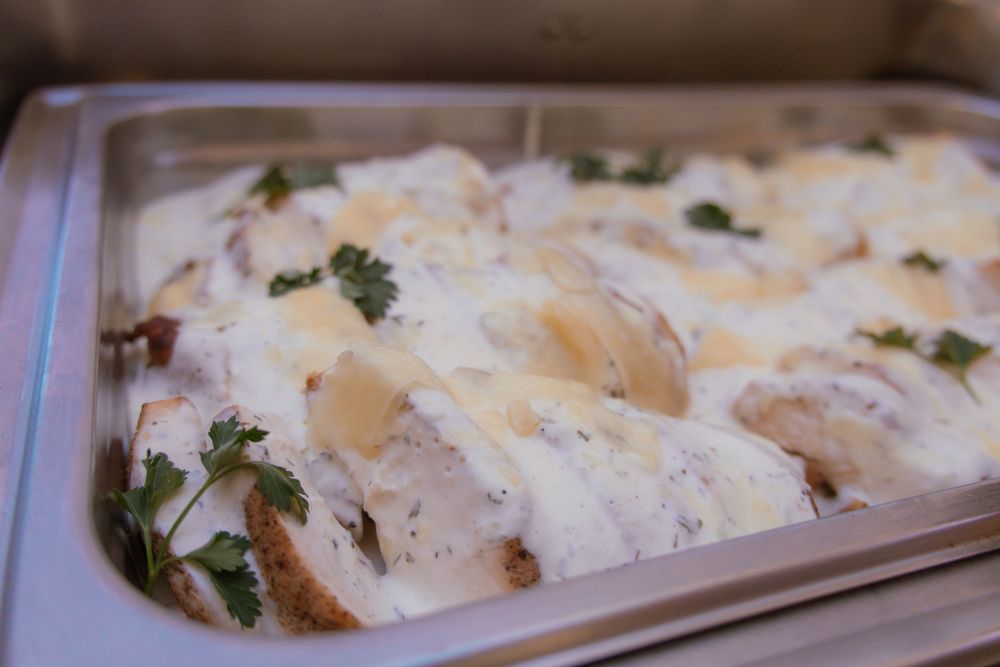 Creamy mushroom sauce over sliced bread garnished with fresh herbs in a white baking dish.