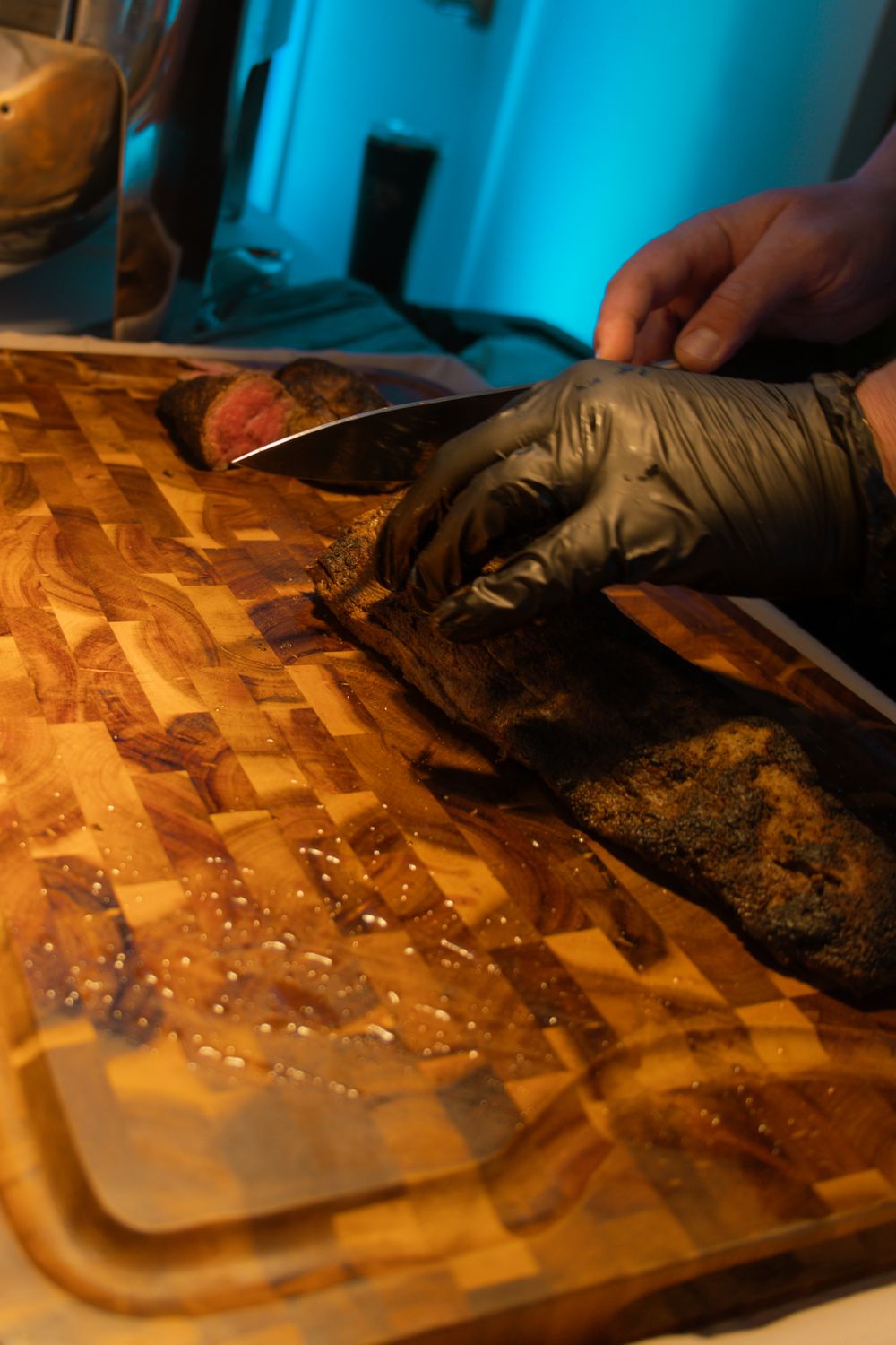 Hands working on a wooden cutting board preparing small dark truffles with powdered ingredients in warm lighting.