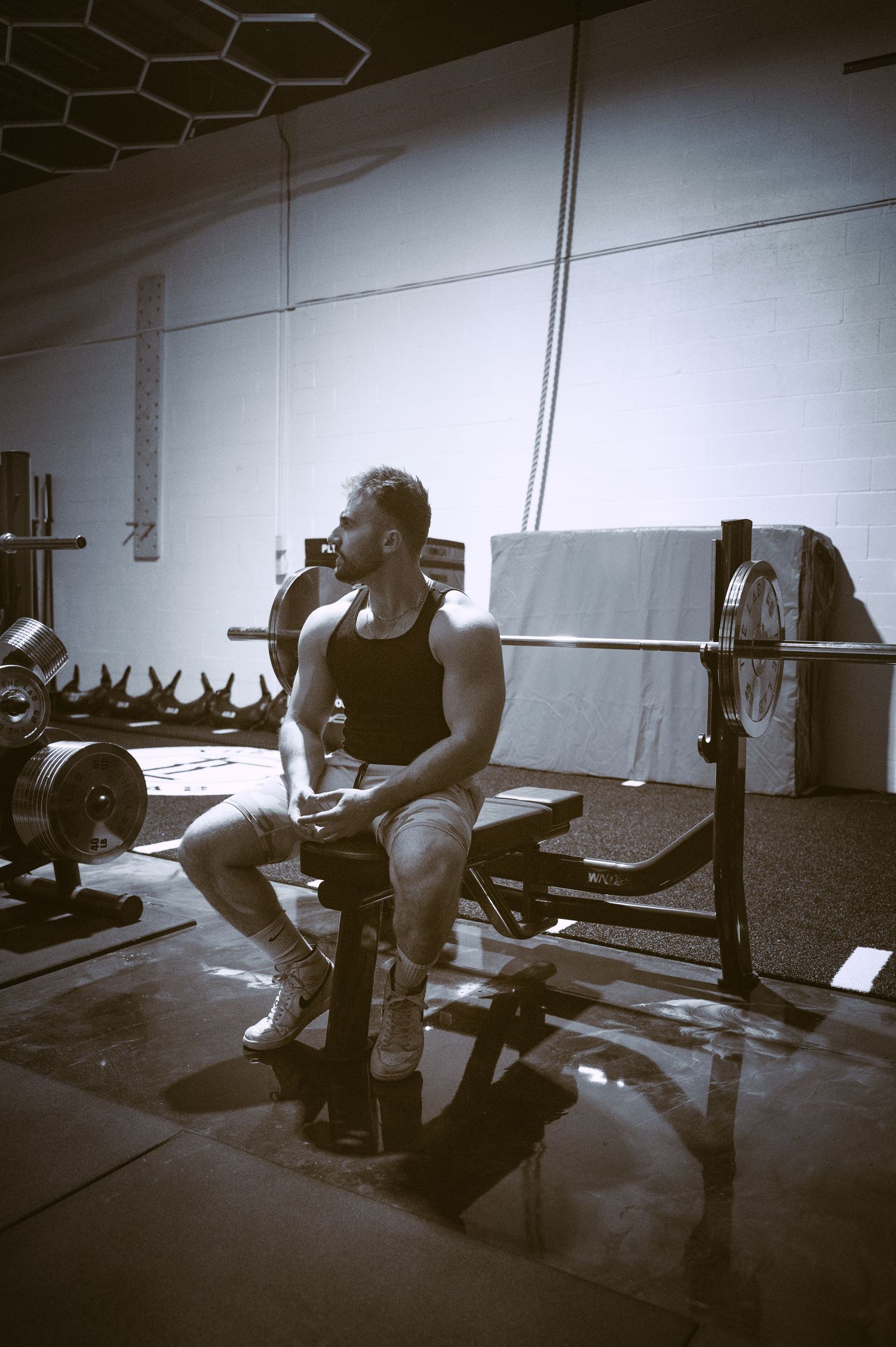 A black and white photo sequence showing a person performing a CrossFit weightlifting movement in a gym setting.
