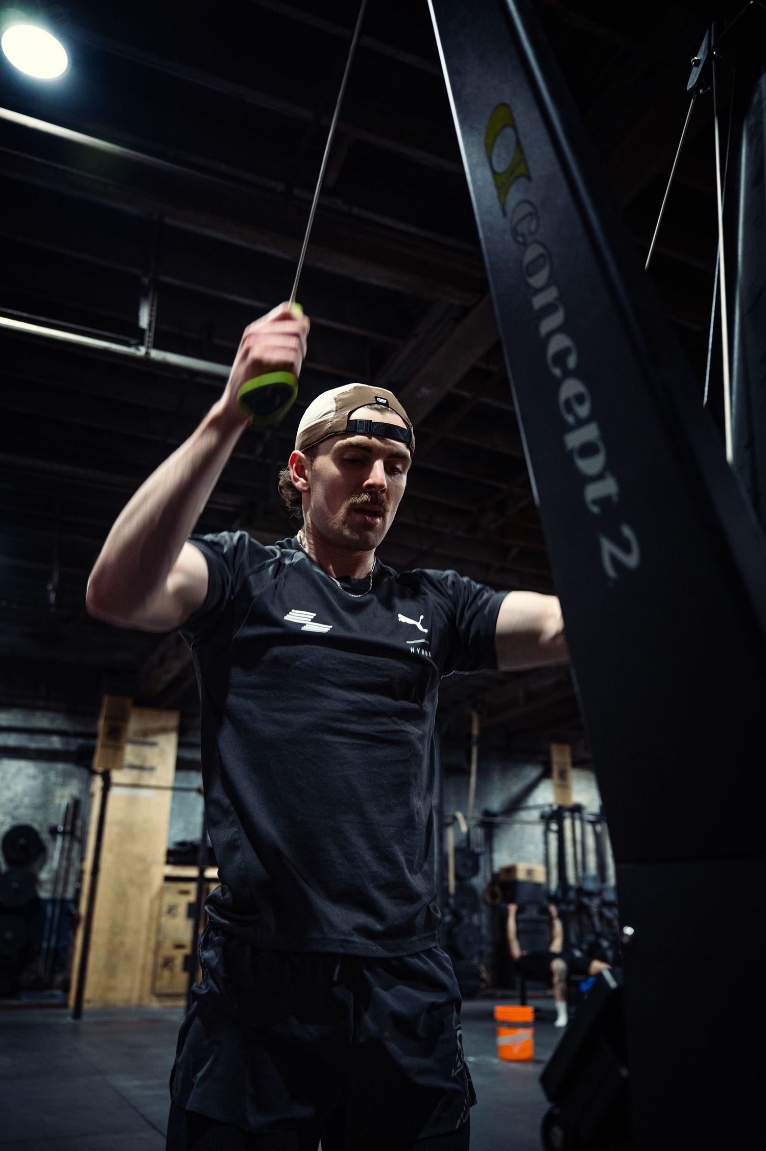 Person in black t-shirt performs dynamic movements against dark gym background in progressive action sequence.