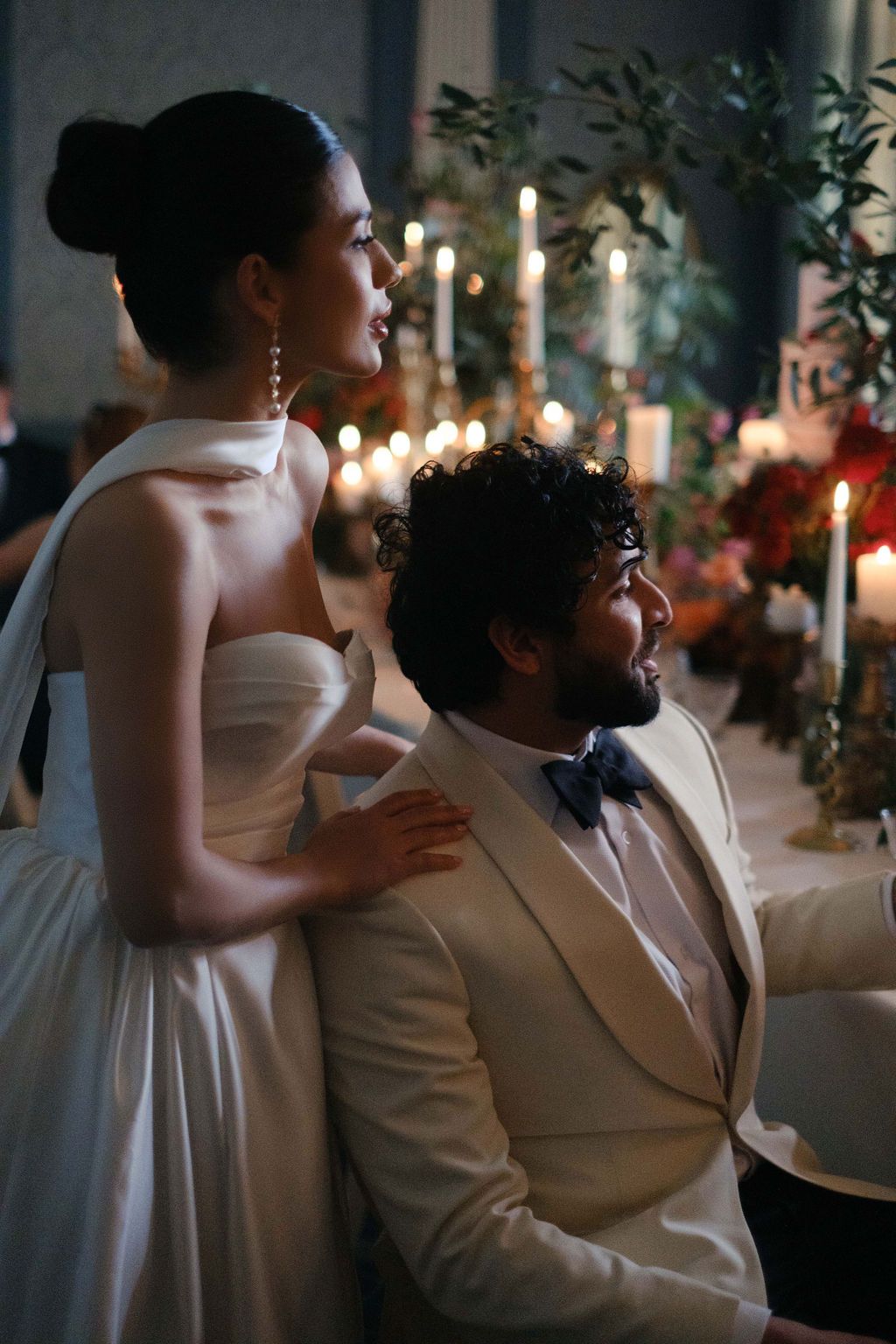 Elegant evening wedding reception with couple in white attire and candlelit ambiance.