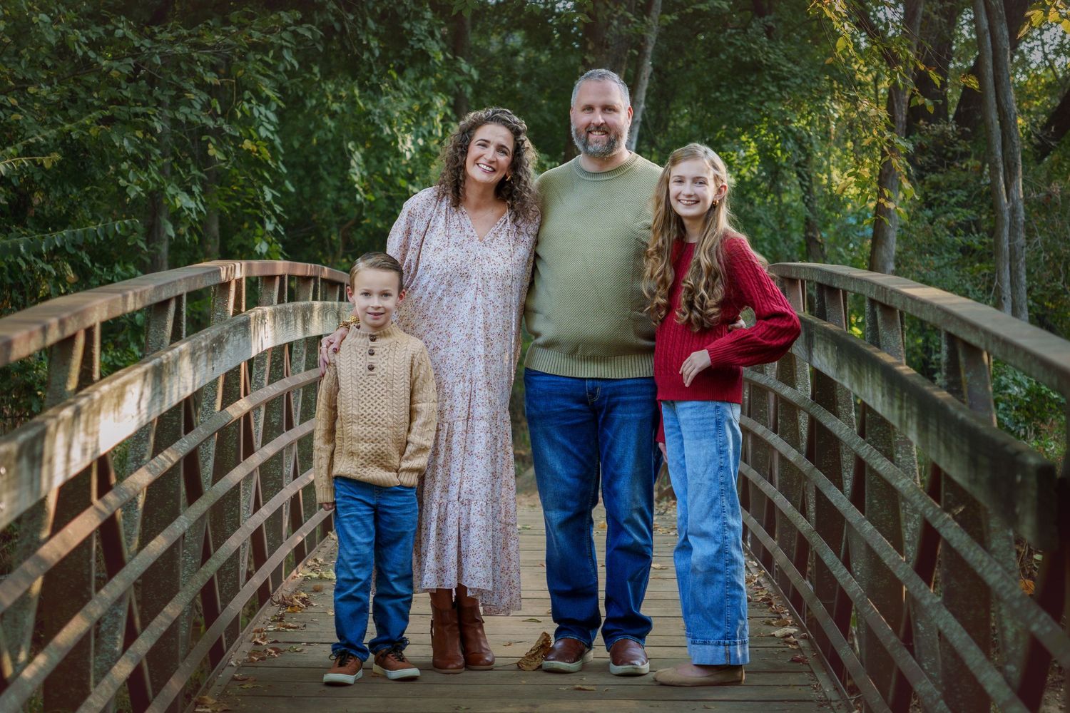 family photo session fall season leaves Colleyville nature center TX family standing on wooden vintage bridge pose candid orange leaves