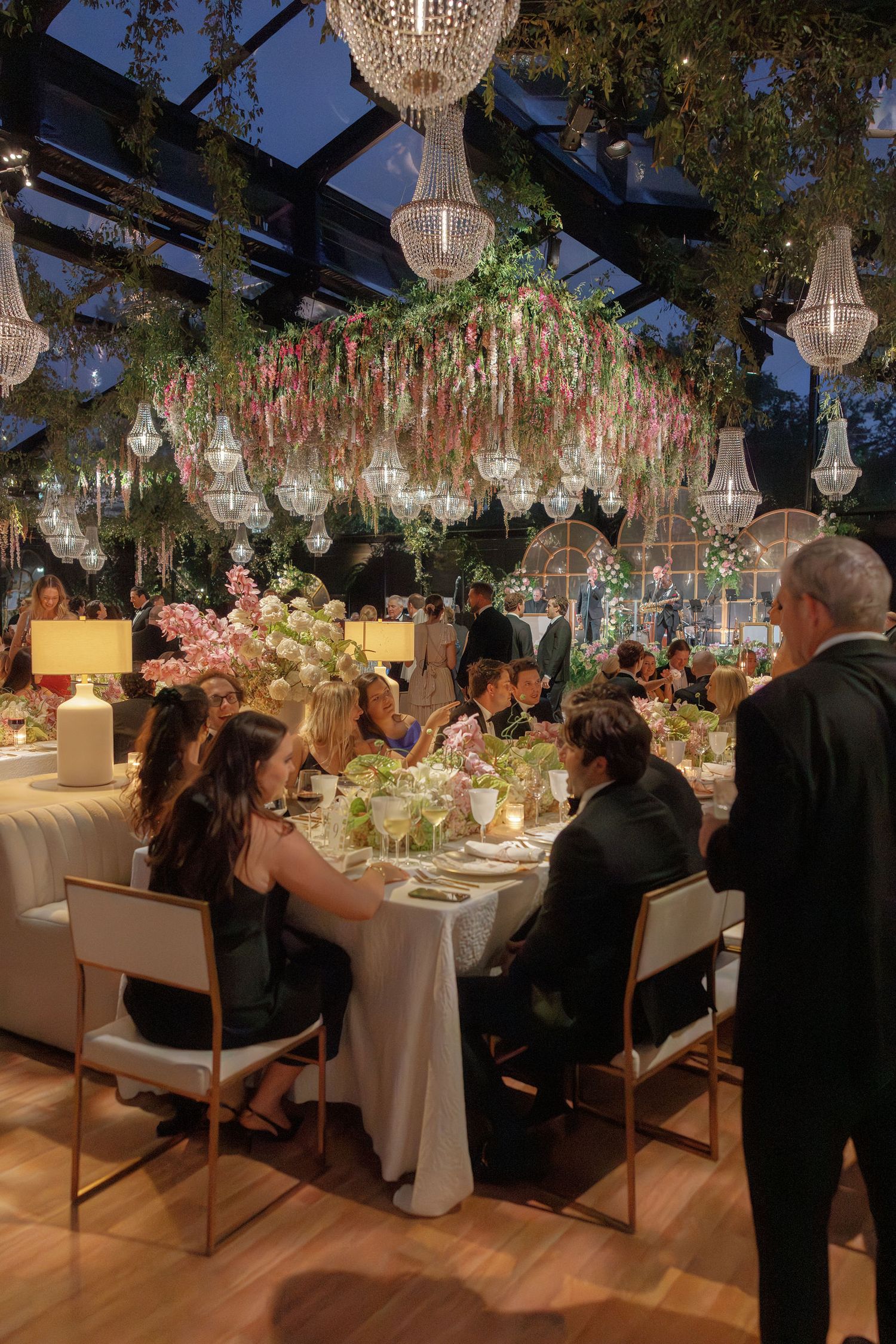 Elegant wedding reception with crystal chandeliers and floral decor featuring long tables set for a luxurious dinner service.