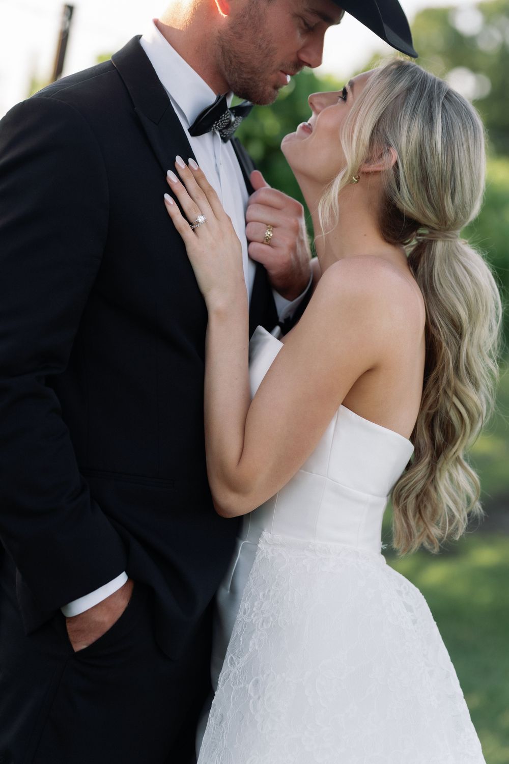 Romantic wedding portrait of a couple in formal attire sharing an intimate moment outdoors.