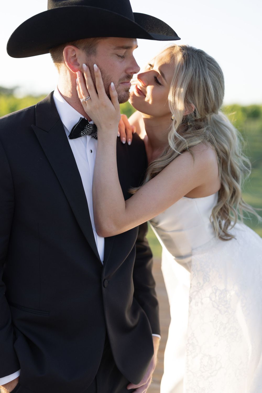 A romantic moment between newlyweds outdoors with golden sunlight and natural scenery.