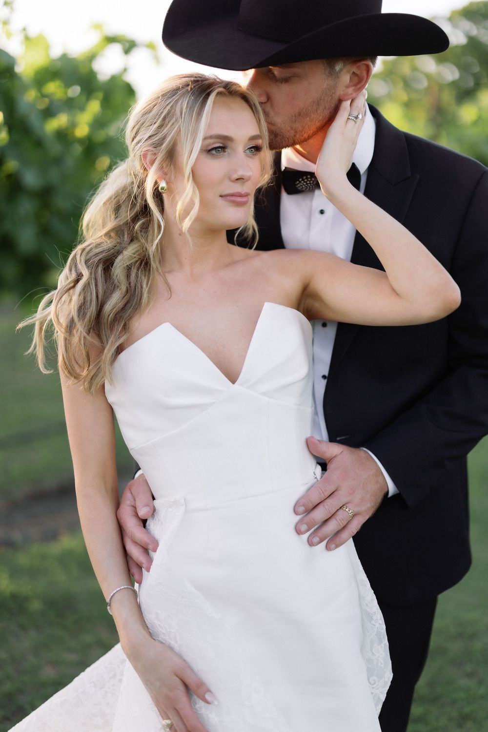 An intimate portrait of newlyweds sharing a tender moment in a garden setting at sunset.
