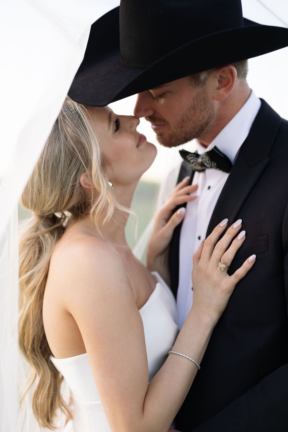 A series of tender moments between newlyweds with the groom in a black cowboy hat and bride in white.
