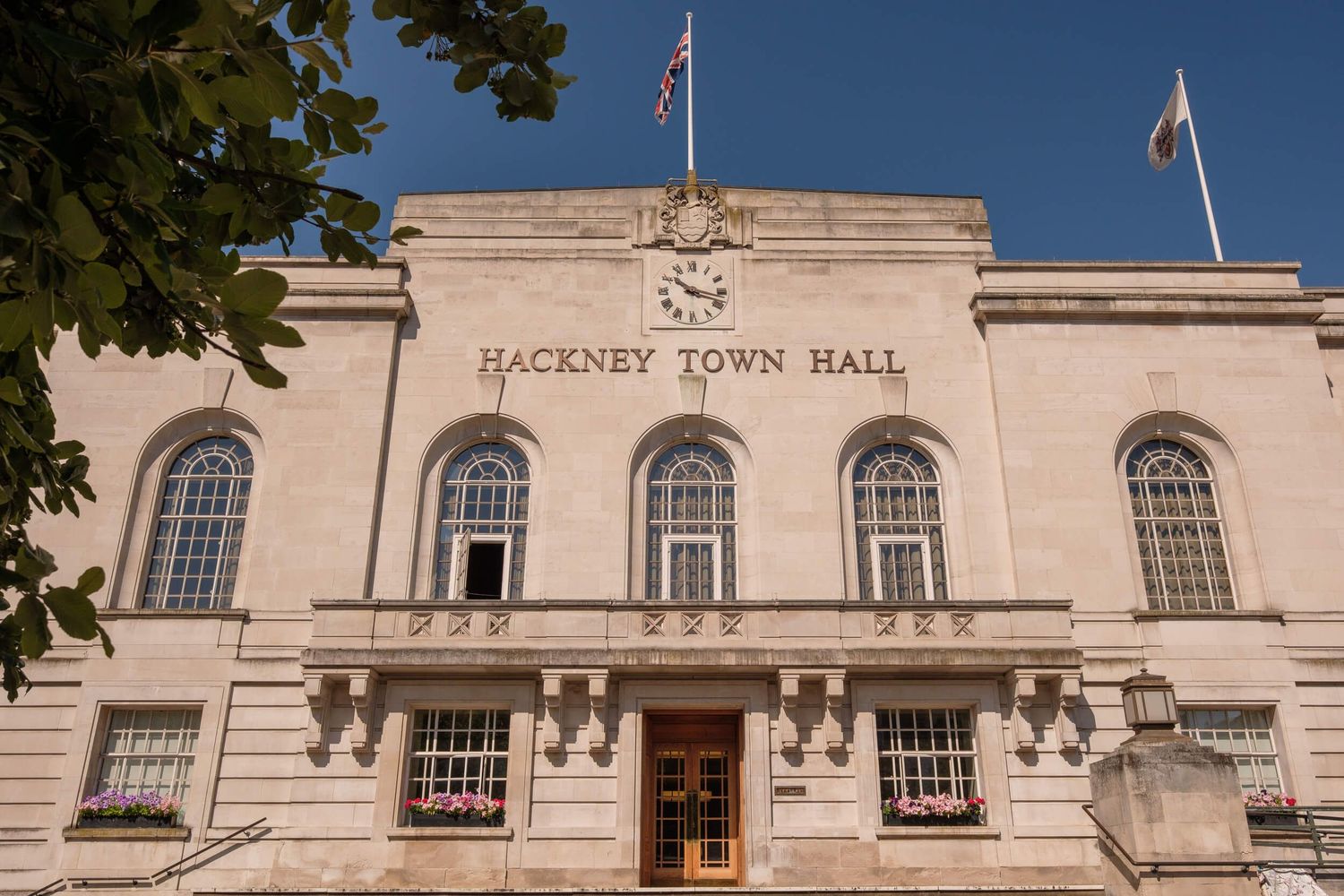 Panoramic exterior view of Hackney Town Hall's historic Art Deco facade with British flag and ornate architectural details.