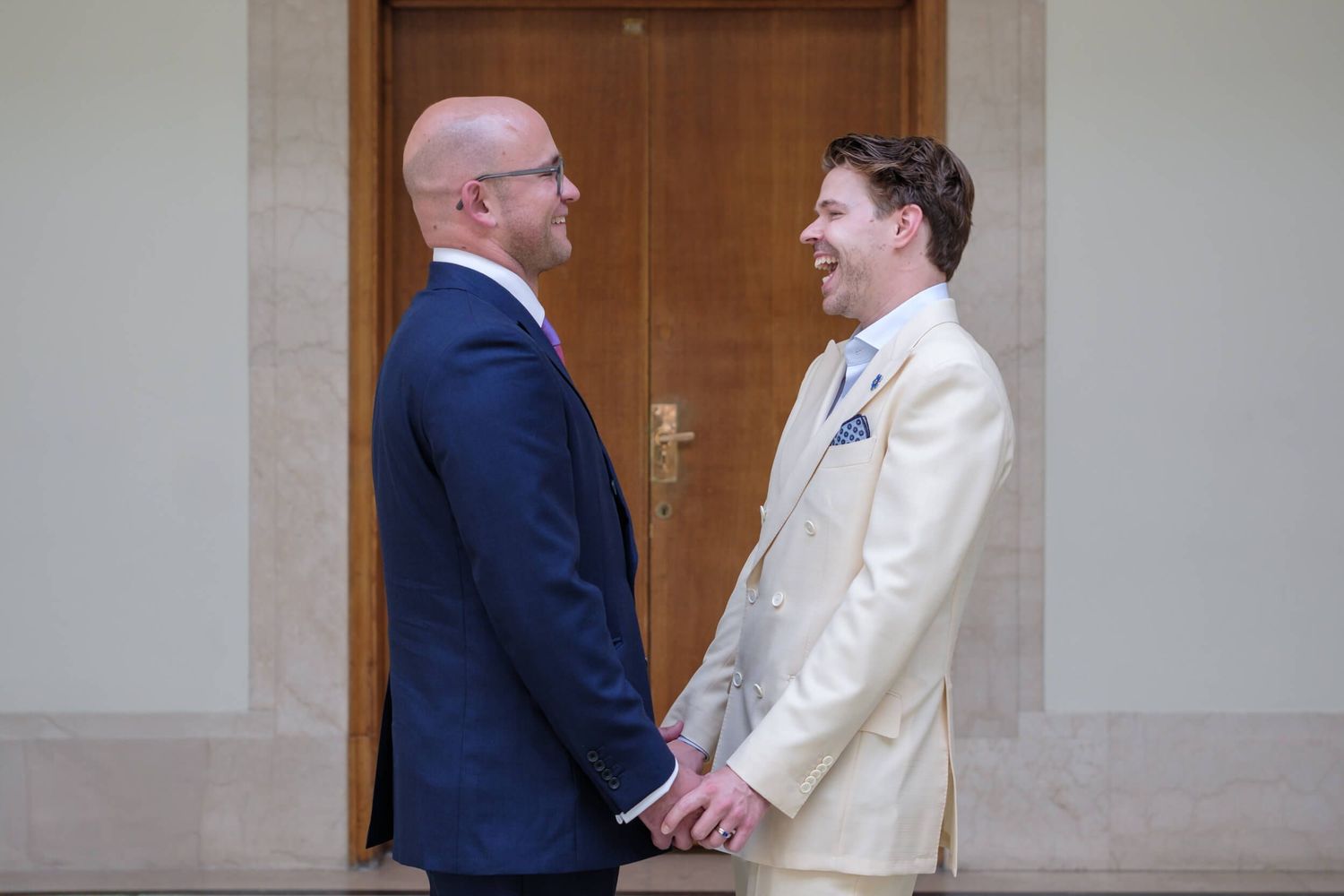 Two people share a joyful moment together while holding hands in formal attire during a wedding celebration.