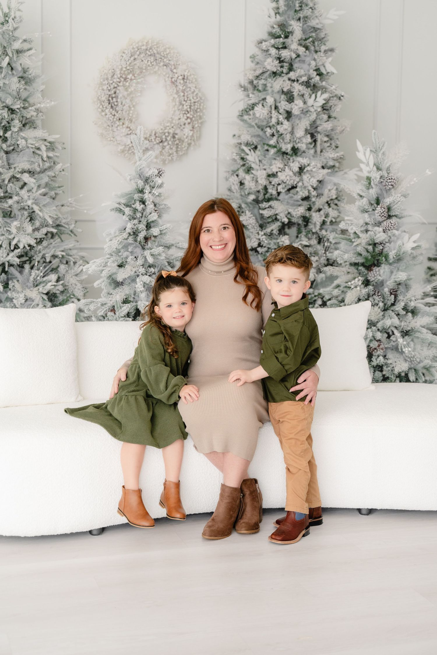 Festive winter photo session with snow-flocked trees creating a magical white backdrop for coordinated family outfits.