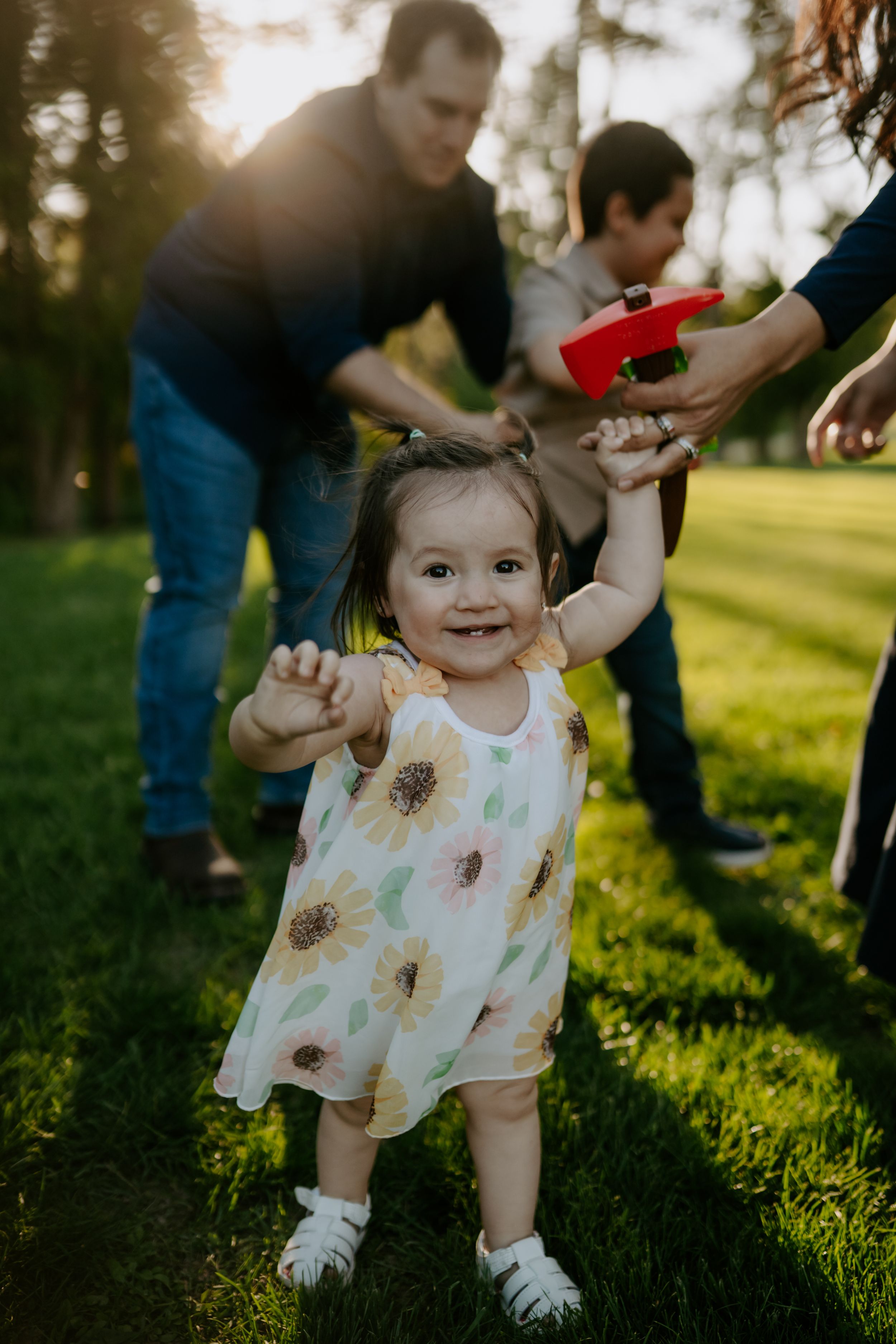 Small child in floral dress playing outdoors in evening sunlight.