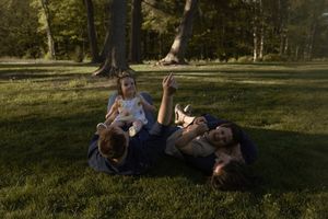 Family enjoying a playful moment together on lush grass during golden hour.