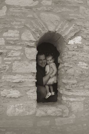 A black and white family portrait framed within a rustic stone window opening.