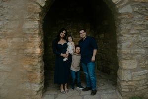 A family poses together inside a stone castle archway during a moody photo session.