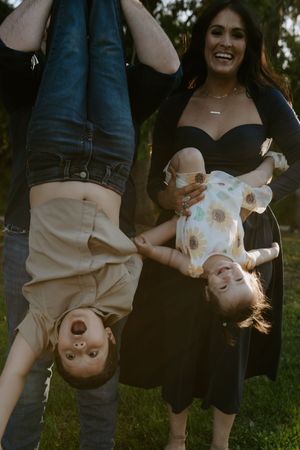 A playful upside-down family photo taken outdoors against a dark background.